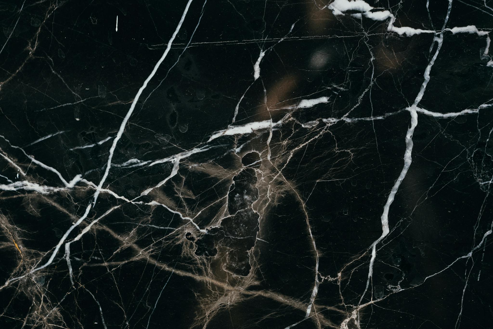 Close-up view of a black marble texture, showcasing intricate white veining patterns.